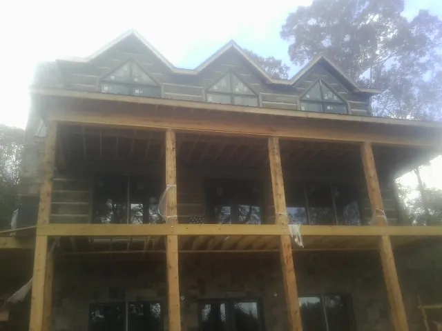 Dormers and porch framing on a large log home under construction — Roof Coating work by our crew in Muldrow