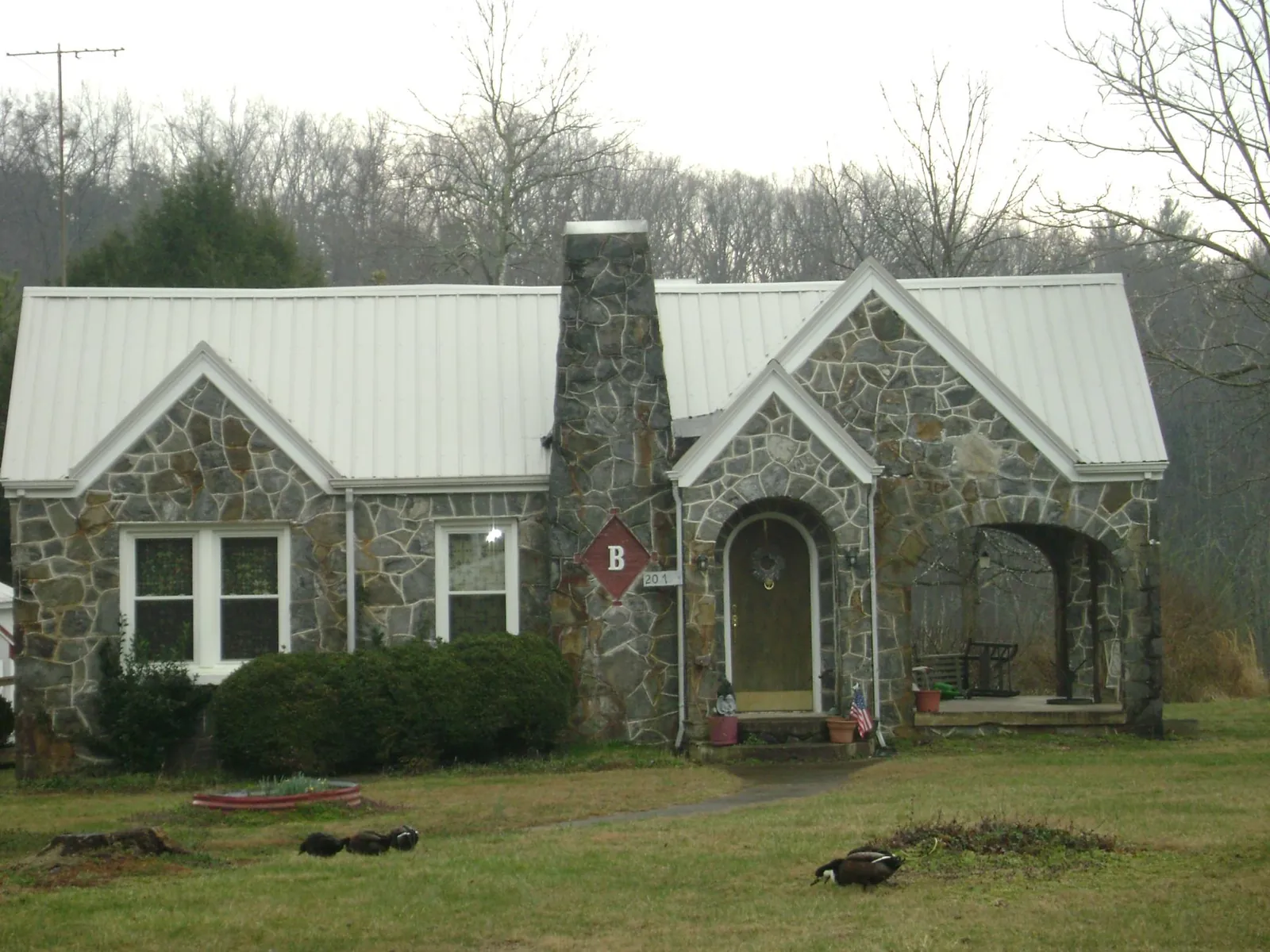 White metal roof on a stone cottage with steep gables in Muldrow