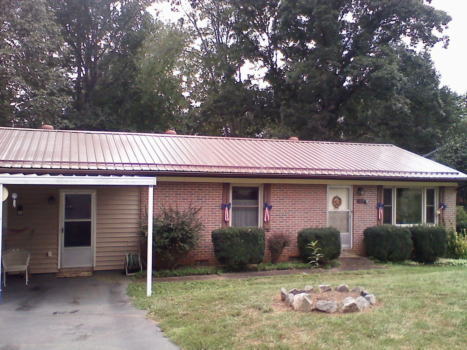 Bronze metal roof and carport on a brick ranch home — Roof Repair work by our crew in Muldrow
