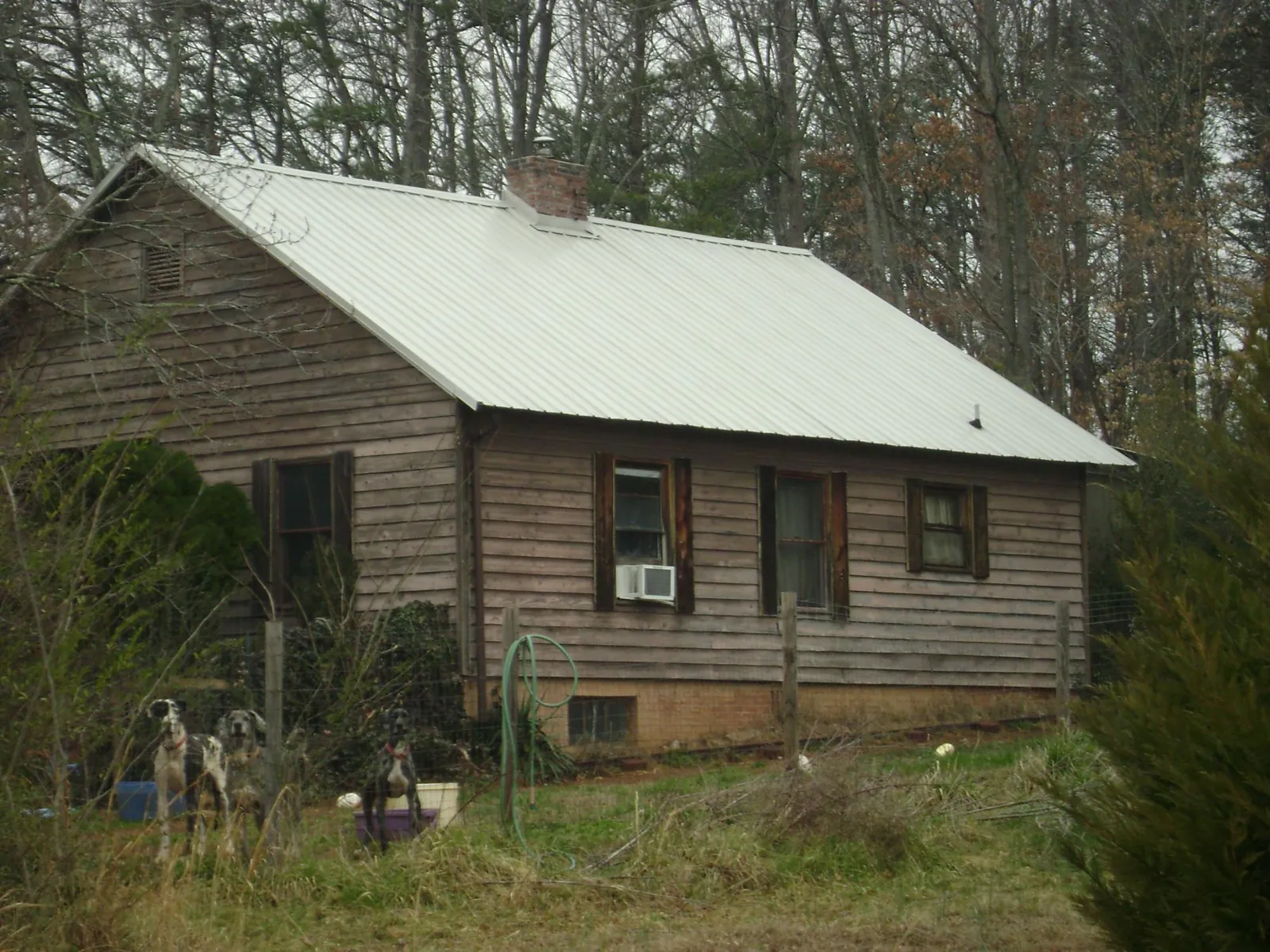 White metal roof on an old wood sided farmhouse, from a Metal Roof Installation job in Muldrow